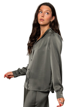 Woman wearing a green satin outfit against a gray background