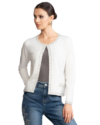 Woman wearing a white cardigan with decorative trim, gray top, and blue jeans against a plain background.