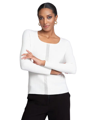 Woman wearing a white cardigan with black pants on a light gray background