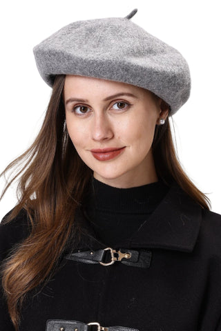 Woman wearing a gray beret and black coat against a white background