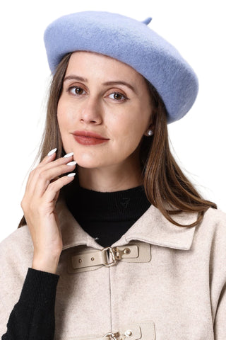 Woman wearing a light blue beret and beige coat against a white background