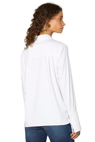 Woman wearing a white shirt and blue jeans against a plain background