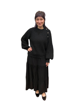 Person wearing a black outfit in a fitting room.