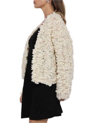 Woman wearing a textured white jacket over a black dress on a white background
