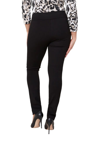 Person wearing black pants with a patterned top on a plain background