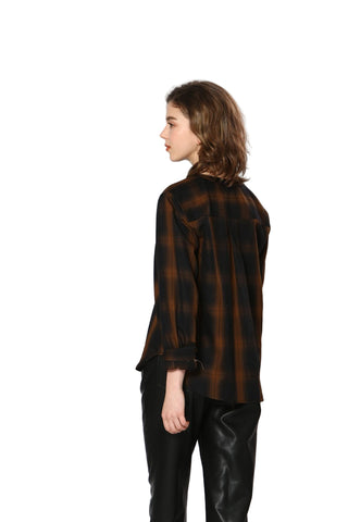 Woman wearing a black and brown plaid shirt on a white background