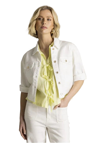 Woman wearing a white jacket over a yellow shirt with a plain background