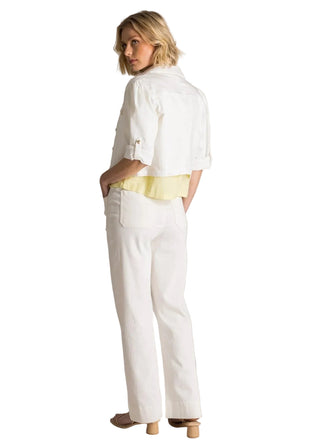 Woman wearing a white outfit with a yellow top against a plain background