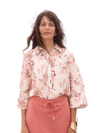 Woman wearing a floral blouse and pink pants outdoors