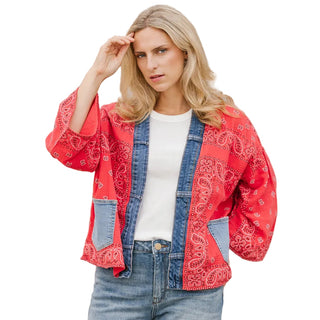 Woman wearing a red bandana print jacket over a denim jacket with a beige background