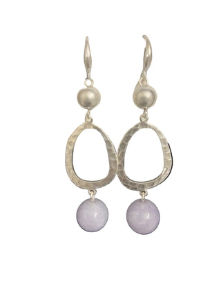 Silver hoop earrings with purple beads on a display card against a black background