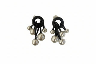 A pair of black and silver dangle earrings featuring black elastic loops and multiple dangling faux pearl beads, displayed on a plain off-white surface.