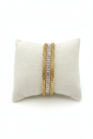 Gold bracelet on a beige fabric cushion against a granite countertop