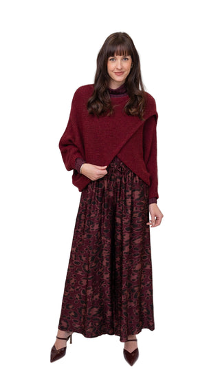 Woman wearing a burgundy sweater and patterned skirt on a white background