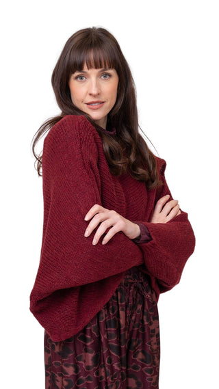 Woman wearing a burgundy sweater with a plain background