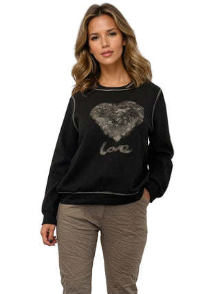 Woman wearing a black sweatshirt with a heart design and 'love' text on a plain background