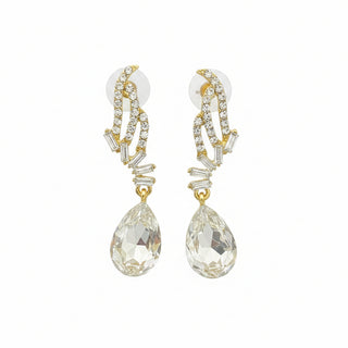 Gold earrings with teardrop-shaped stones on a textured surface