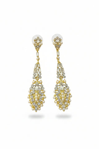 Gold and crystal drop earrings on a textured brown surface