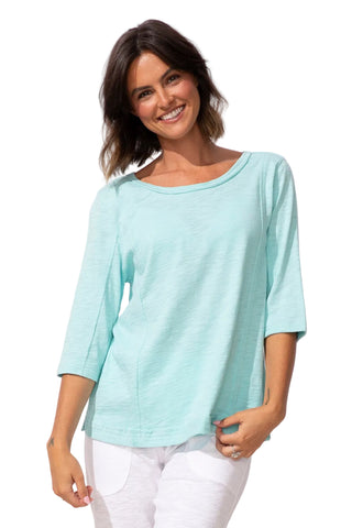 Woman wearing a light blue top and white pants on a white background