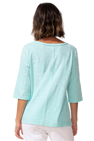 Person wearing a light blue top with white pants on a plain background