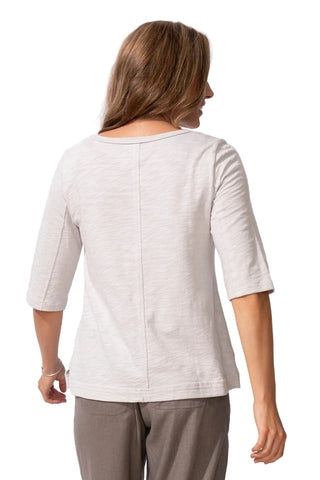 Woman wearing a light-colored top and gray pants on a white background