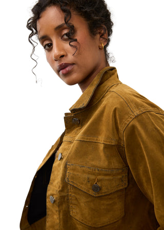 A close-up shot of a model wearing a mustard yellow corduroy utility jacket against a plain light gray background.