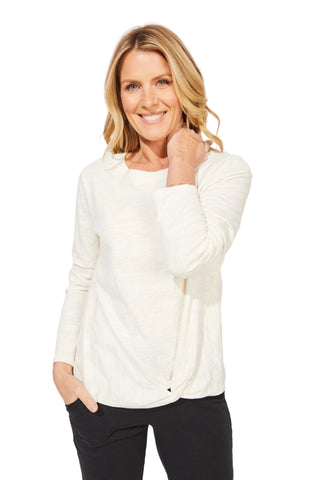 Woman wearing a white blouse and black pants against a light gray background