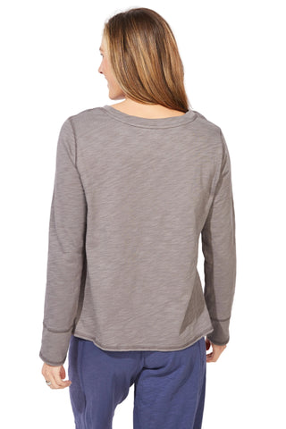 Person wearing a gray long-sleeve top and blue pants on a white background