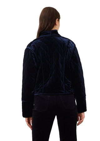 A model viewed from the back wearing a dark navy blue quilted velvet jacket and matching dark pants against a plain light background.