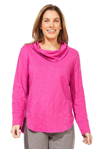 Woman wearing a bright pink long-sleeve top with a cowl neck on a white background