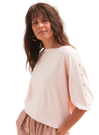 Woman wearing a light pink blouse with a blurred natural background