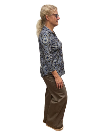 Person standing in a fitting room wearing a blue patterned shirt and brown pants.