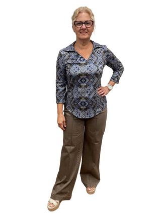 Person wearing a blue patterned shirt and brown pants in a fitting room.
