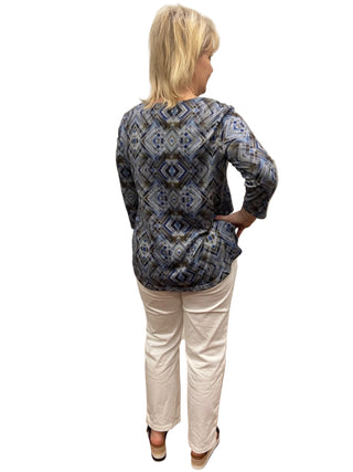 Person wearing a blue patterned top and white pants in a fitting room.