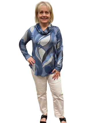 Woman wearing a blue patterned top and white pants in a fitting room.