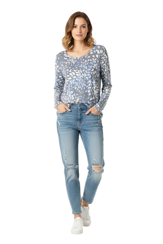A woman modeling a long-sleeve scoop-neck top with a blue and white abstract leaf pattern, paired with light-wash distressed jeans and white sneakers, against a plain white studio background.