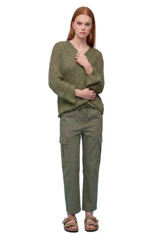 Woman wearing a green knitted sweater and cargo pants on a light blue background