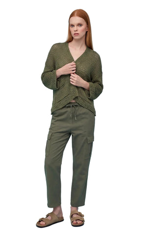 Woman wearing a green knitted sweater and cargo pants on a light blue background