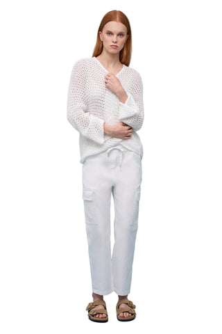 Woman wearing a white knit sweater and pants on a light blue background