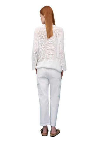 Person wearing a white textured top and white pants on a light blue background