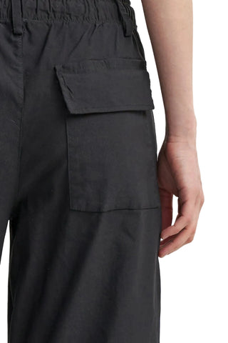 Close-up of a person wearing dark charcoal gray cargo pants, showing a side pocket and the hand of the model.