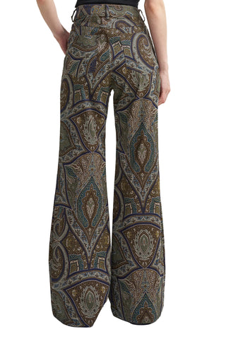 Wide-leg trousers with an intricate paisley pattern in olive green, brown, beige, and blue, shown on a model from the back against a white studio background.