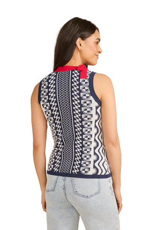 Woman wearing a sleeveless patterned top with a red collar against a beige background