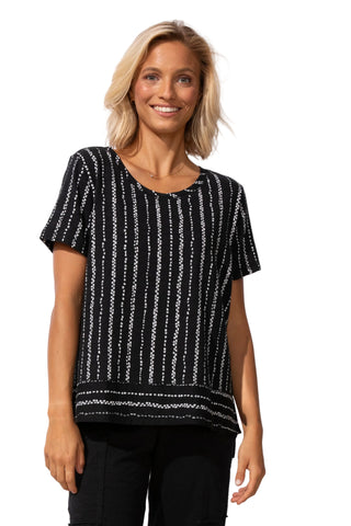 Woman wearing a black and white patterned top against a white background