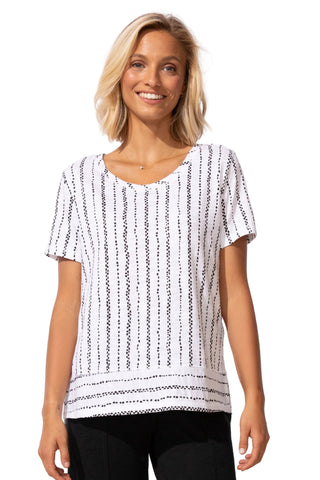 Woman wearing a black and white patterned top against a plain background