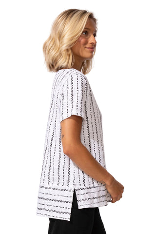 Woman wearing a white and black patterned top against a plain background