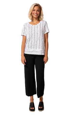 Woman wearing a black and white striped shirt and black pants against a white background