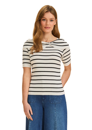 Woman wearing a black and white striped shirt with blue jeans on a beige background