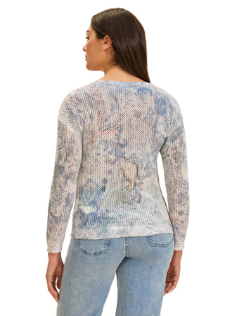 Woman wearing a light blue patterned sweater and jeans on a beige background