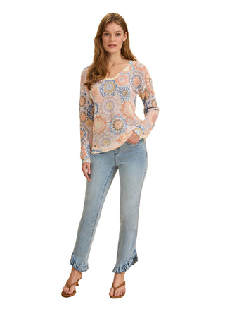 Woman wearing a patterned blouse and light blue jeans on a beige background